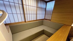 Un coin salon avec un banc rembourré, une table en bois et un paravent de style shoji.