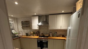 A modern kitchen with white cabinets, a stainless steel range hood, a built-in oven, and a Samsung refrigerator.