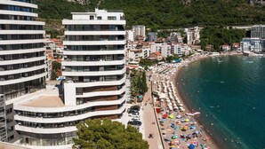 A coastal hotel with multiple floors, a beachside location, and a view of the sea. - Royalis Suites Rafailovici - Beachfront Sea View Apartments (Becici)