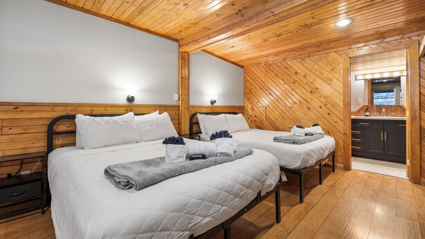 Una stanza con due letti, pareti in legno e un angolo cottura.