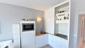 A compact kitchen with a microwave, sink, and built-in shelves. - Studio in Duinbergen by the Sailing Club (Knokke-Heist)