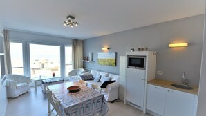 A modern living room with a dining area, a sofa, a TV, and a kitchen with a sink. - Studio in Duinbergen by the Sailing Club (Knokke-Heist)