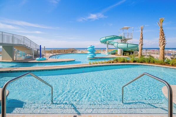 A swimming pool with a water slide and a lifeguard tower.