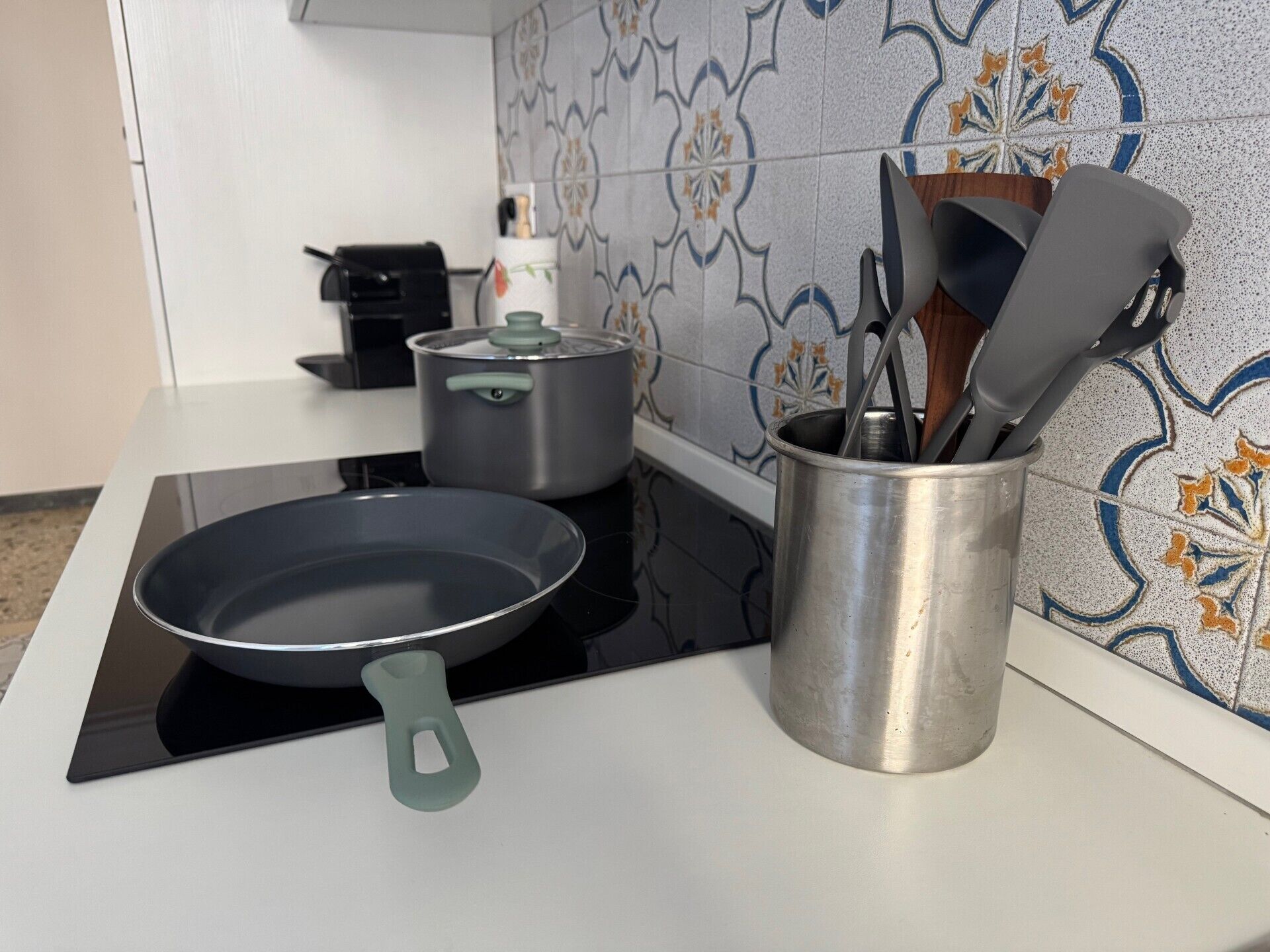 Una cucina con un fornello, una pentola, una padella e un portauova.