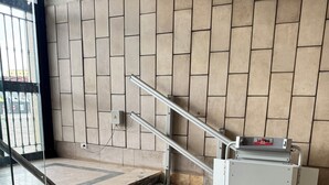 A staircase with metal handrails, a tiled wall, and a control panel on the right.