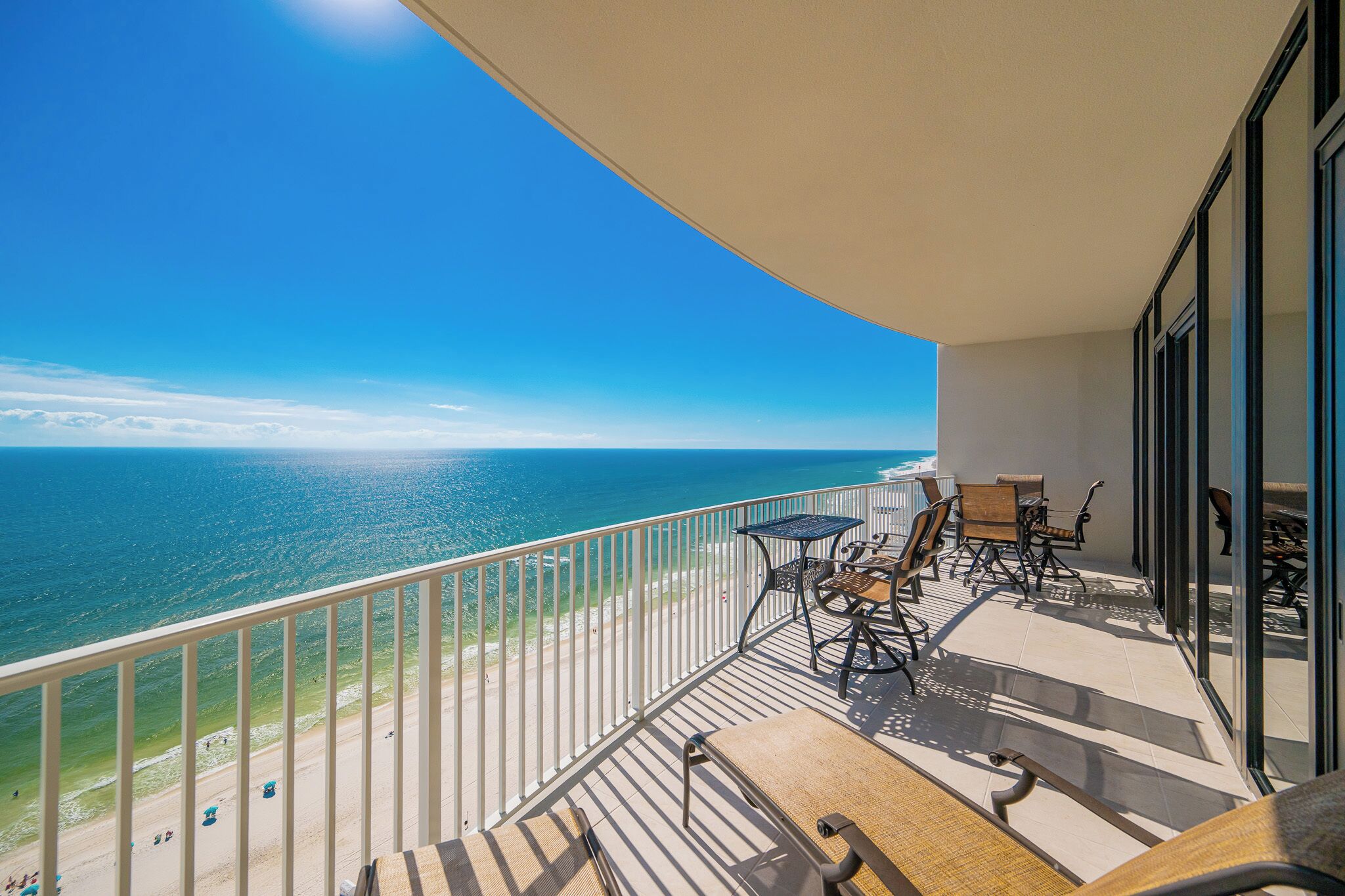 A balcony with a view of the ocean, furnished with chairs and a table.