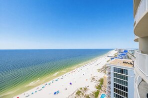 A beach view from a high-rise building with a pool and outdoor seating.