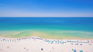 A beach with white sand, clear turquoise water, and umbrellas.
