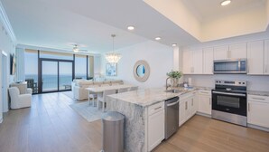A modern kitchen with a large island, stainless steel appliances, and a view to the outside.