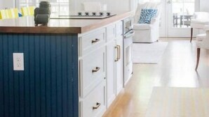 A modern kitchen with a blue island, white cabinets, and pendant lights. - Large Common Areas, Quiet Street, Golf Cart Available! (Carolina Beach)