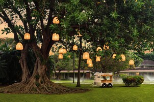 A tree with hanging lanterns, a water feature, and a trailer in a landscaped area.