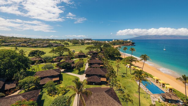 Un resort con varias construcciones tipo cabaña, una piscina y una playa.