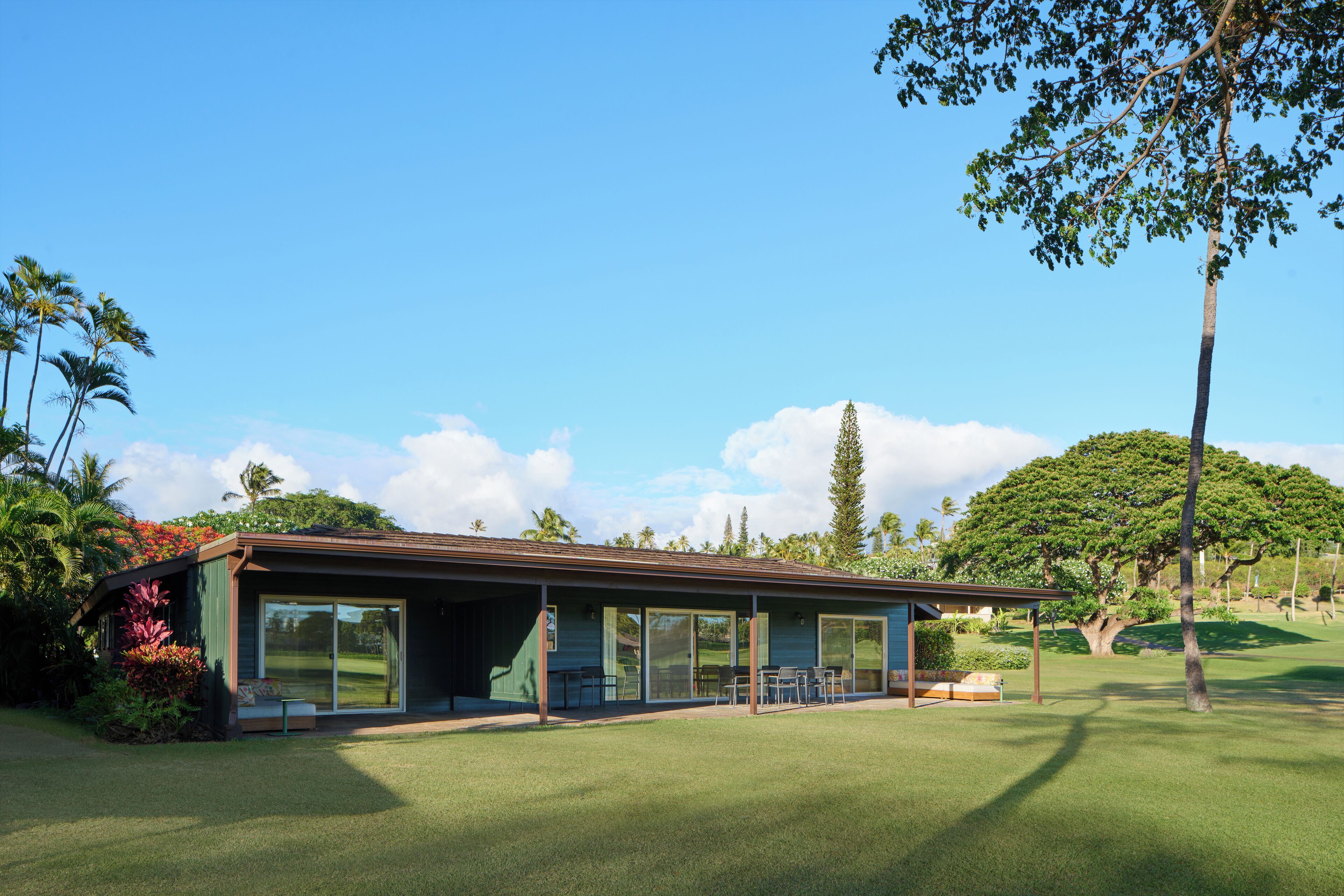 Une maison moderne dotée d’un patio couvert, de grandes portes-fenêtres coulissantes et d’une pelouse bien entretenue.