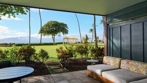 Un patio con sofá y mesa, vista a un campo de golf y un pabellón.