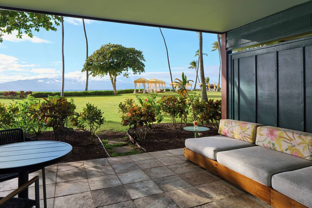 Un patio con sofá y mesa, vista a un campo de golf y un pabellón.