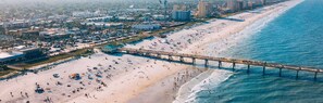 An aerial view of a beach with a pier, adjacent buildings, and a coastal cityscape. - Luxury Beach Home Sauna Cold Plunge E-bikes (Jacksonville Beach)