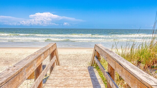 A wooden boardwalk leading to a sandy beach with the ocean in the background. - Luxury Beach Home Sauna Cold Plunge E-bikes (Jacksonville Beach)