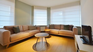 A modern living room with two sofas, a coffee table, and a TV stand. - Apartment in Knokke Near the Beach (Knokke-Heist)