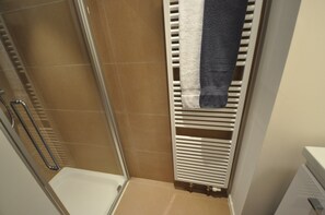 A shower area with a glass door, a white towel rack, and a white radiator. - Apartment in Duinbergen by Sailing Club (Knokke-Heist)
