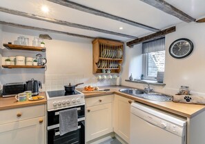 Een koelkast, een oven, een vaatwasser, kookgerei, borden en bestek
