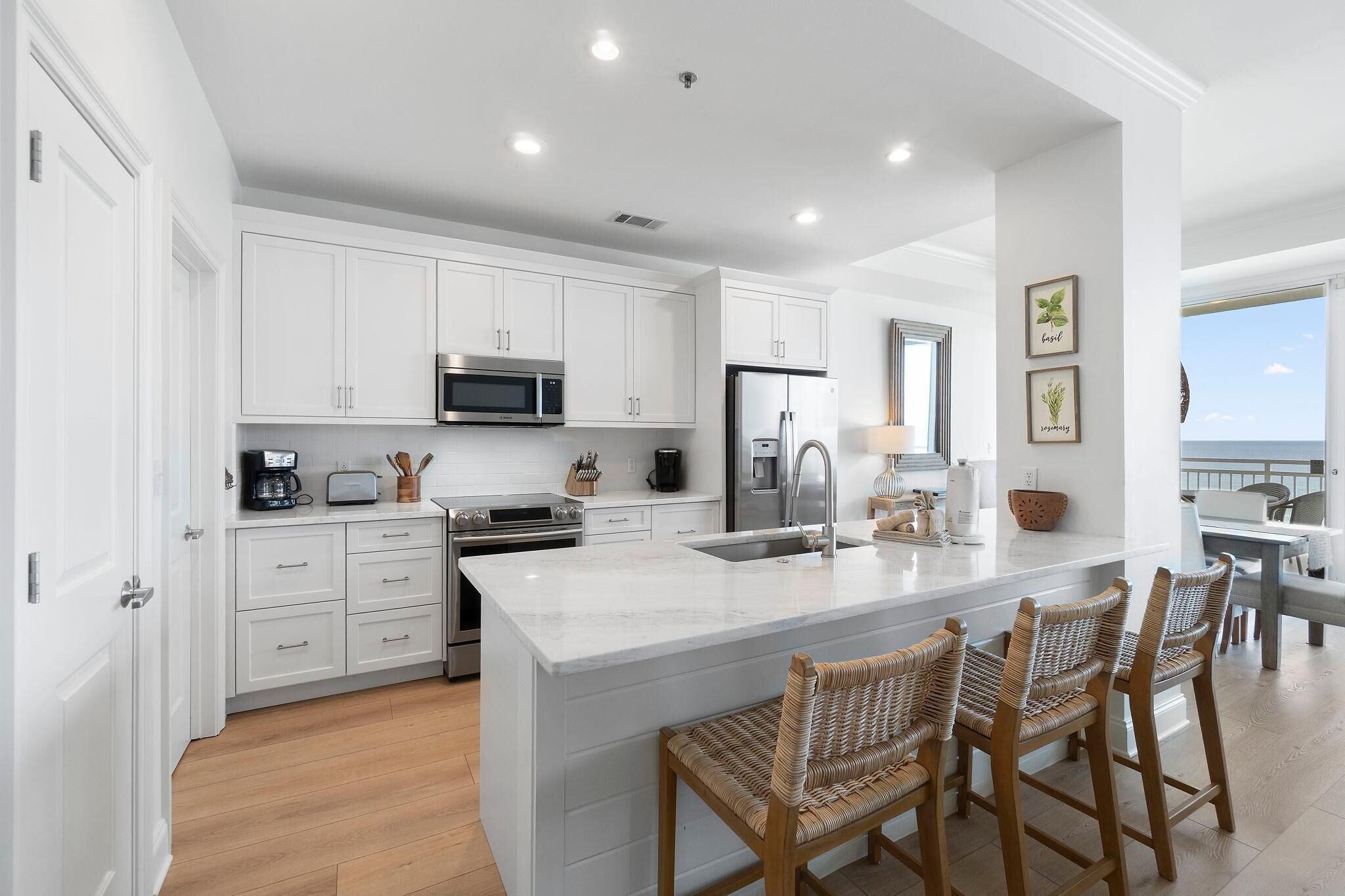 A modern kitchen with white cabinetry, stainless steel appliances, and a large island with bar stools.