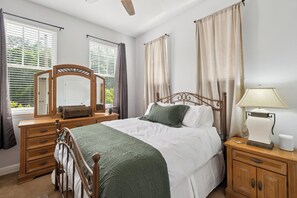 A bedroom with a bed, dresser, mirror, bedside table, and curtains.
