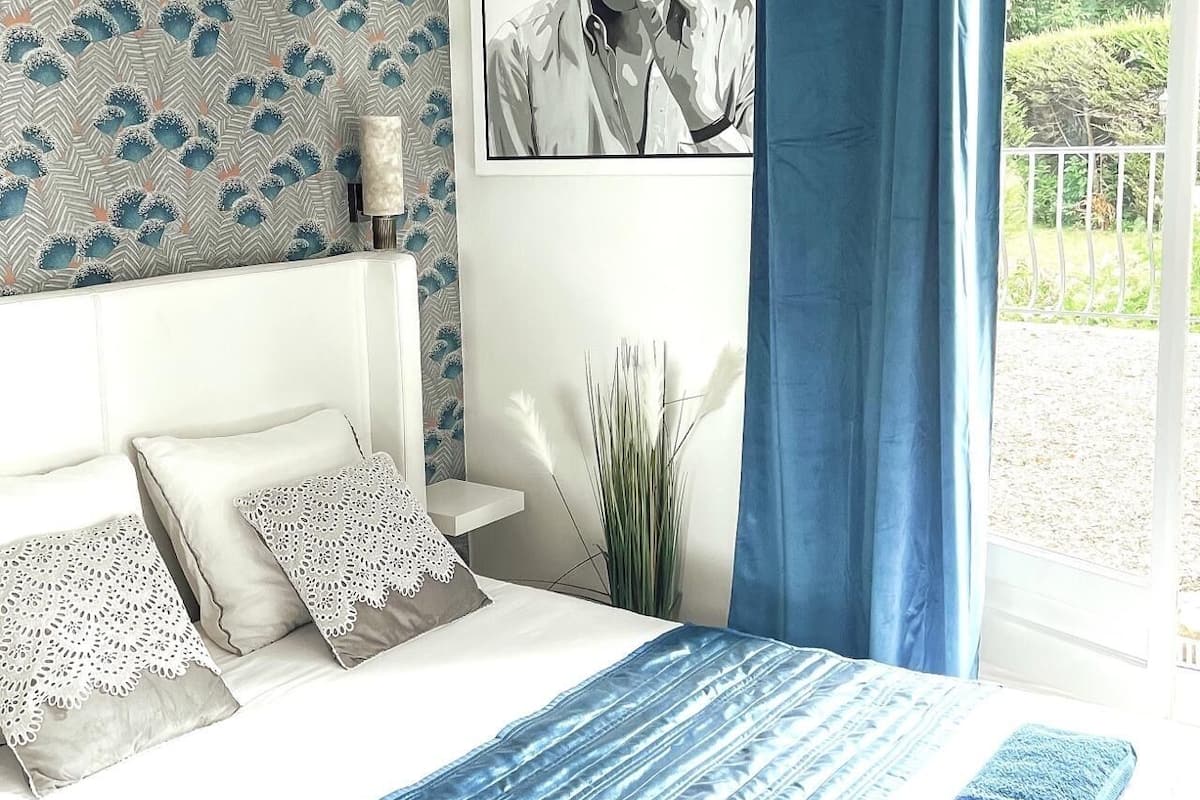 Ein Schlafzimmer mit einem Bett, Kissen, einer blauen Decke und einem gerahmten Bild an der Wand.