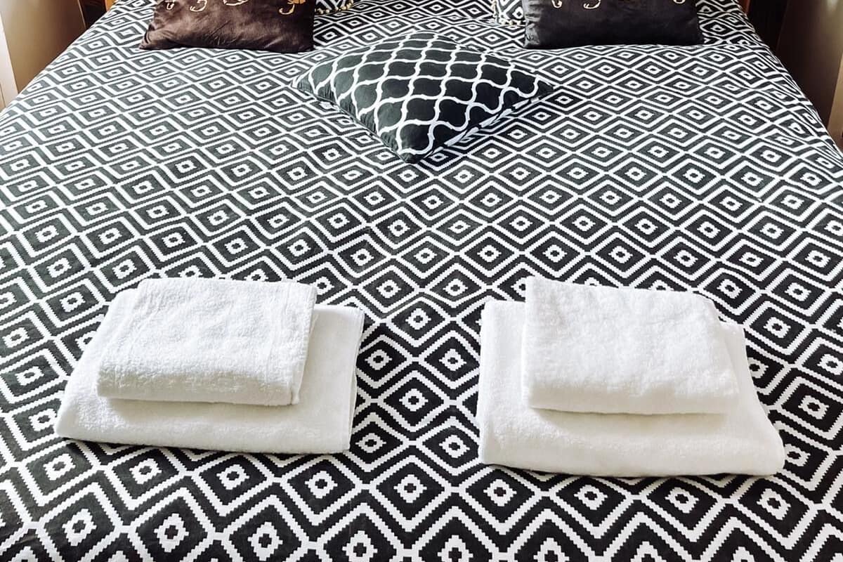 Ein Bett mit einem gemusterten Überwurf und zwei Kissen mit geometrischen Mustern.