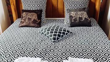 A bed with a patterned bedspread and two pillows with geometric designs.