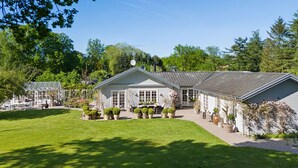 A large, single-story house with a well-maintained lawn and multiple potted plants. - Enchanting 5- bedroom villa in Hornbæk (Hornbæk)