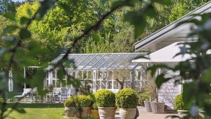 A greenhouse with a glass roof, surrounded by potted plants and outdoor furniture. - Enchanting 5- bedroom villa in Hornbæk (Hornbæk)