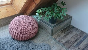 Un rincón acogedor con un pouf de punto, una planta en maceta y un banco de madera.