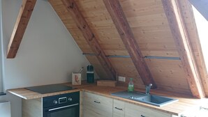 Una cocina compacta con vigas de madera, horno integrado y un lavamanos.