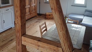 Una habitación con pisos de madera, una mesa de comedor, un sofá, un armario y una ventana.