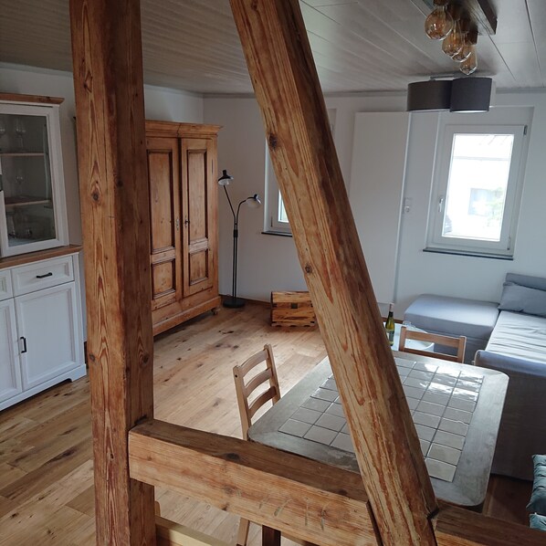 Una habitación con pisos de madera, una mesa de comedor, un sofá, un armario y una ventana.