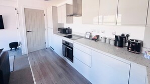 A modern kitchen with white cabinets, a built-in microwave, and a coffee maker. - The Hop Store, HU1. Experience city living in a converted brewery. (Kingston upon Hull)