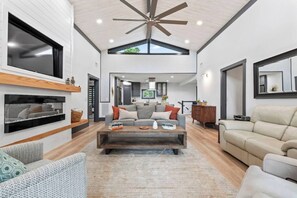 A spacious living room with a high ceiling, a fireplace, a sofa set, and a coffee table.