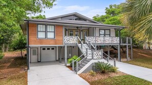 A modern two-story house with a covered front porch, a staircase with decorative railings, and a garage.
