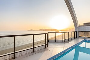 Balcón de hotel moderno con vista a la playa y al atardecer.