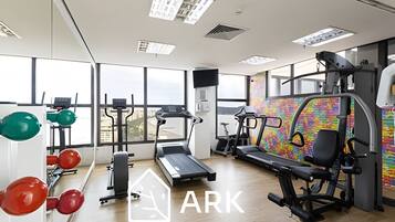 Un gimnasio con equipo cardiovascular, máquinas de pesas y una cinta de correr.