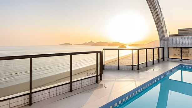 Een modern balkon van een hotel met uitzicht op strand en zonsondergang.