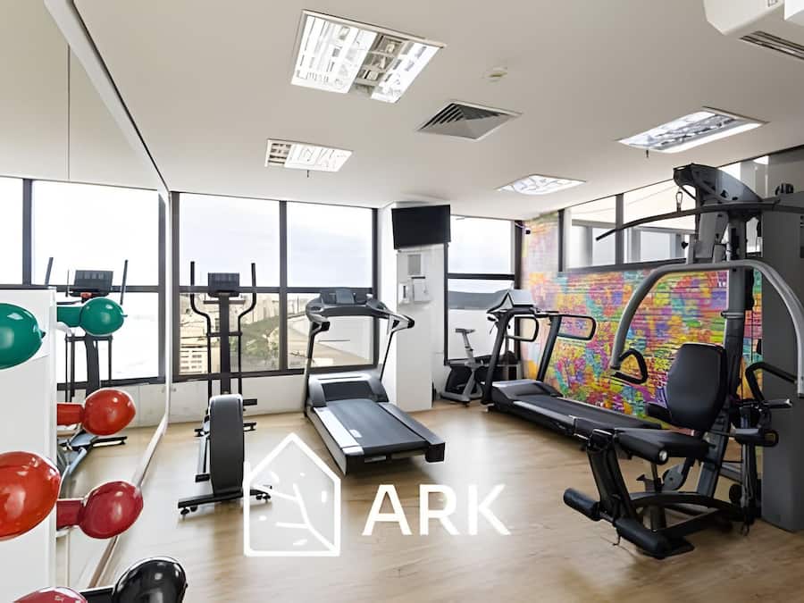 Een fitnessruimte met cardioapparatuur, krachttoestellen en een loopband.