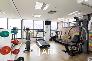 Une salle de sport équipée de machines de cardio, d’appareils de musculation et d’un tapis de course.