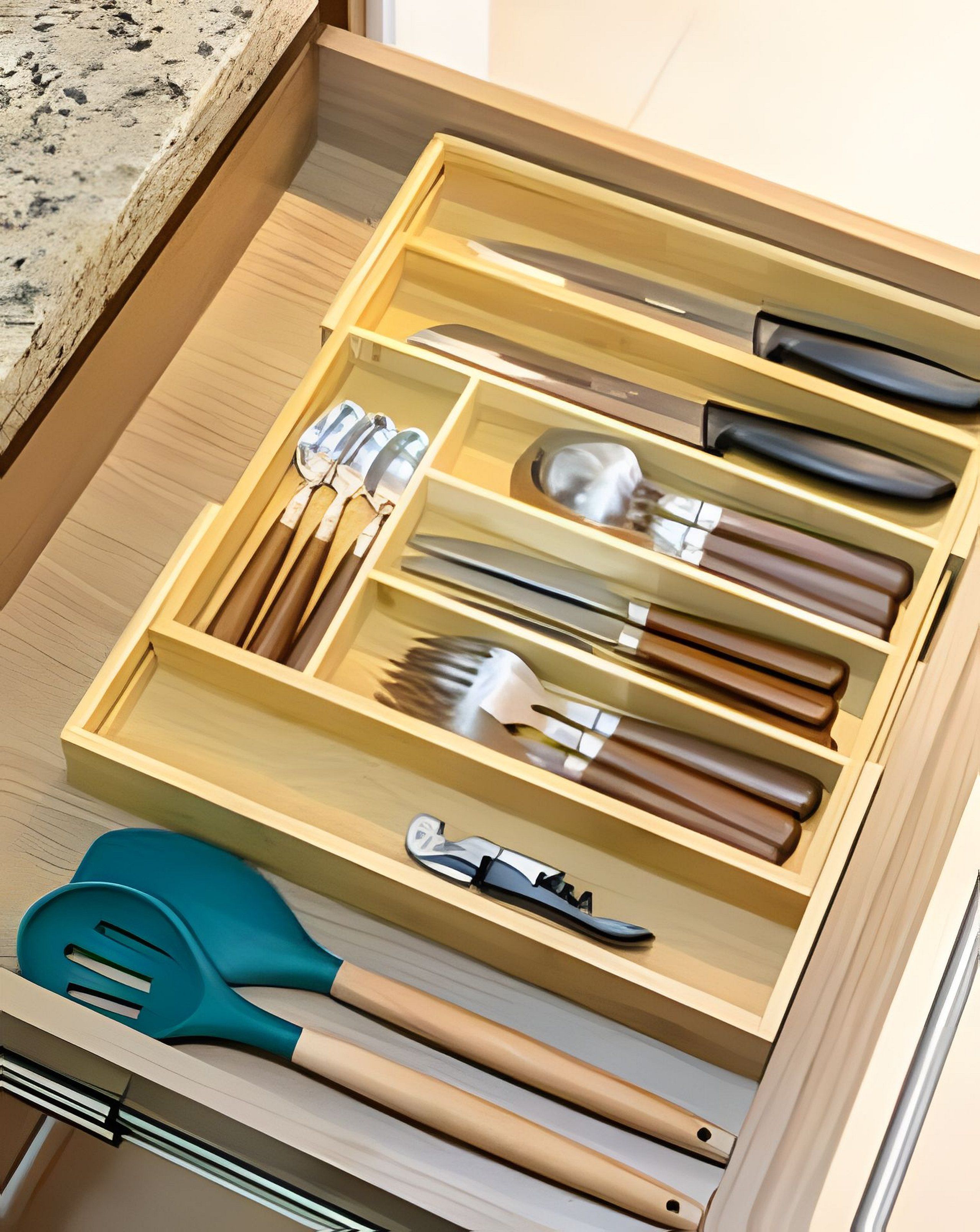 Un cajón con varios utensilios de cocina, incluyendo cuchillos, cucharas y una espátula.