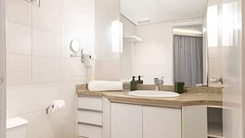 Un baño moderno con inodoro, lavabo, espejo y ducha.