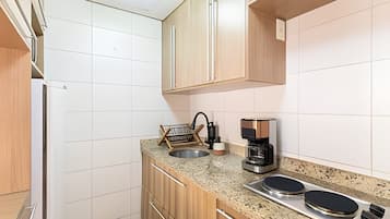 Cocina compacta con lavamanos, cafetera y dos placas de inducción.