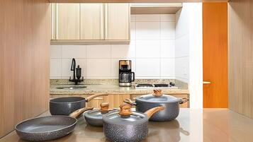 A modern kitchen with granite countertops, a coffee maker, and stoneware pots.