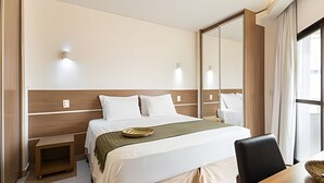 Una habitación de hotel con cama, mesitas de noche, escritorio y una silla.