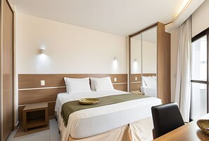 Una habitación de hotel con cama, mesitas de noche, escritorio y una silla.