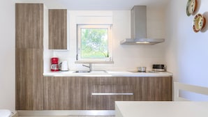 Una cocina moderna con armarios de madera, una ventana, un lavamanos de acero inoxidable, una cafetera y una estufa.